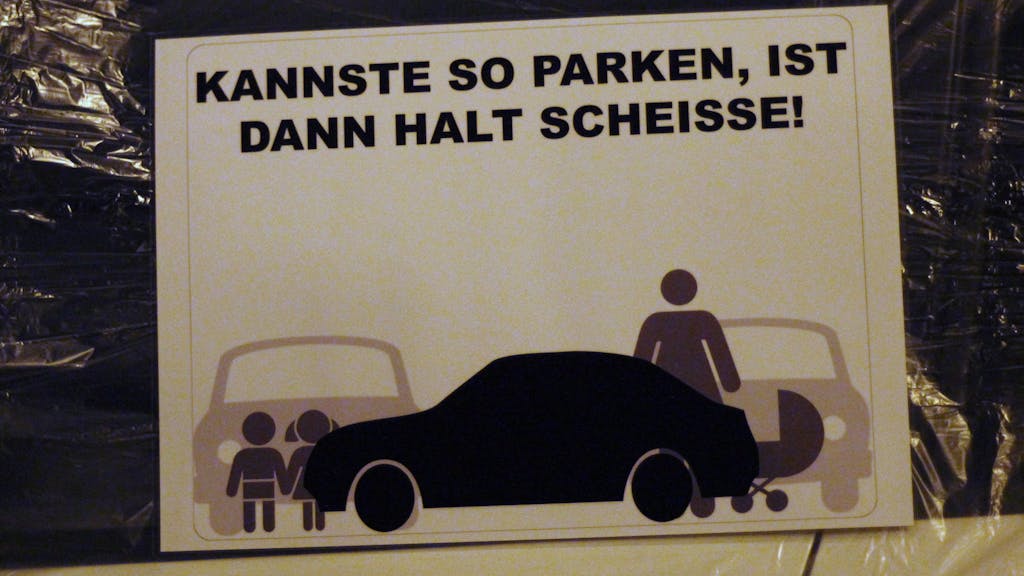Das Symbolfoto zeigt einen Zettel an einer Autoscheibe mit den Worten "Kannste so parken, ist dann halt scheisse!".