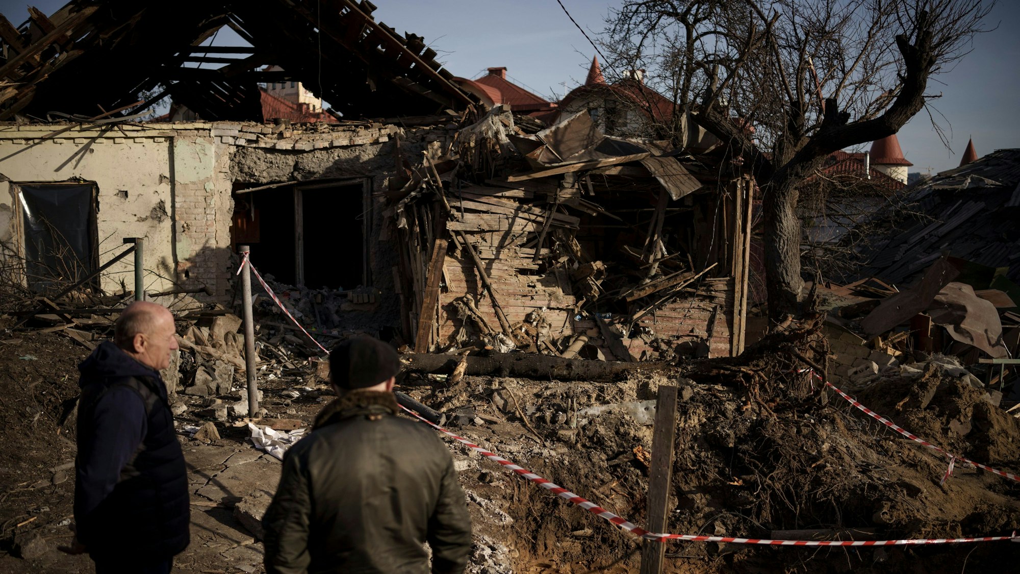 02.01.2023, Ukraine, Kiew: Zwei Männer stehen neben Gebäuden, die bei einem Angriff beschädigt wurden.