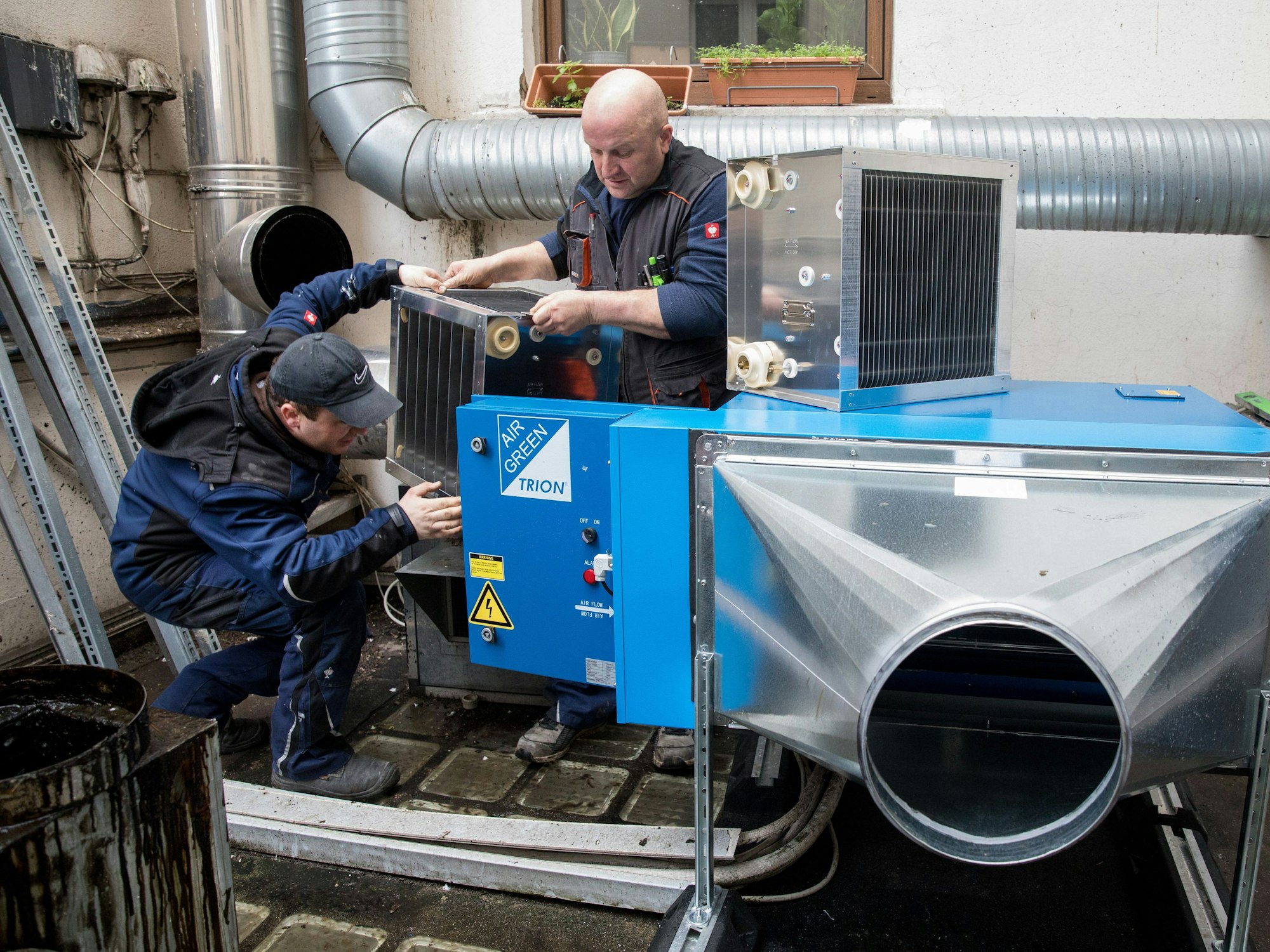 Arbeiter installieren einen großen Filter in einer Halle. Damit sollen Ausstöße in der Kölner Weidengasse reduziert werden.