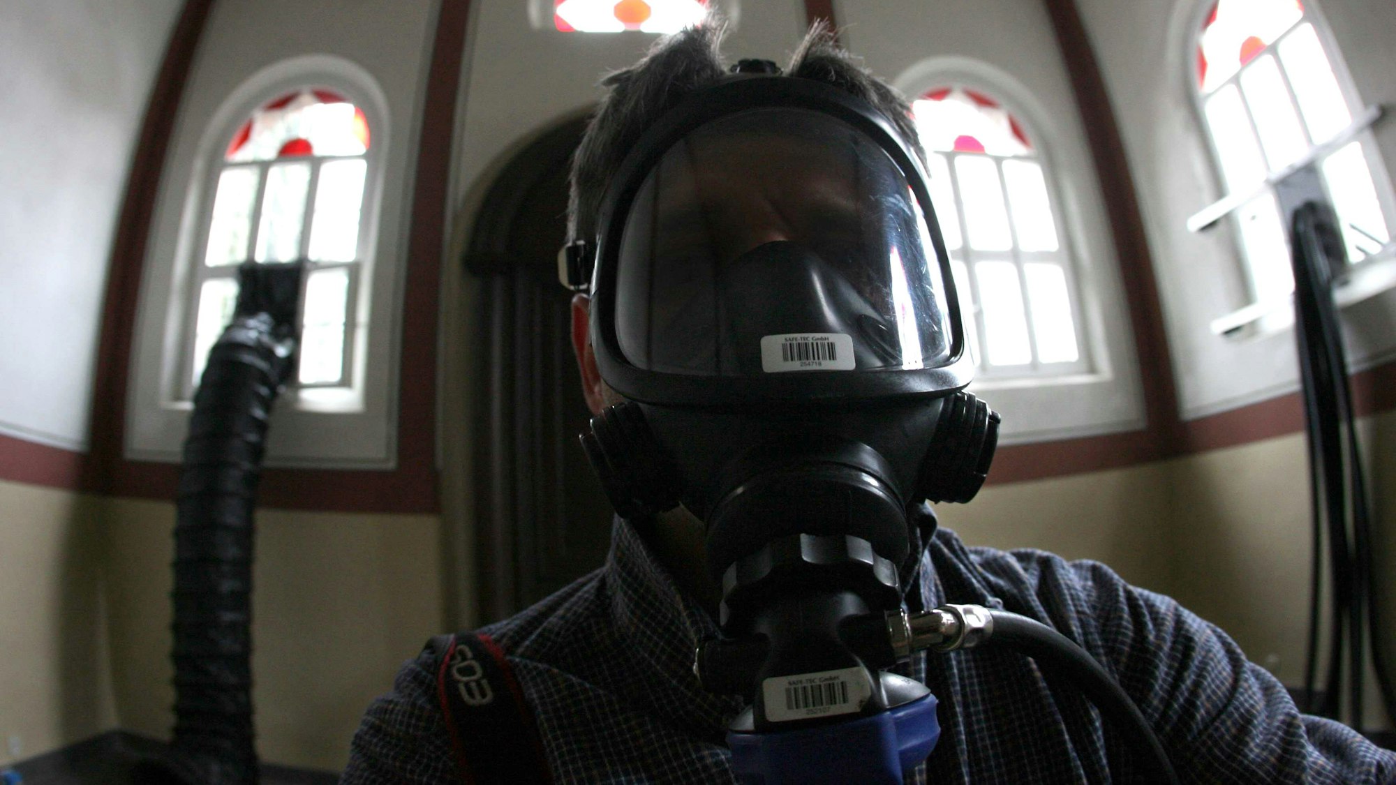 Ein Besucher mit einer umluftunabhängigen Schutzmaske steht während der Kunstaktion 245 Kubikmeter Autoabgase in der Synagoge in Stommeln.