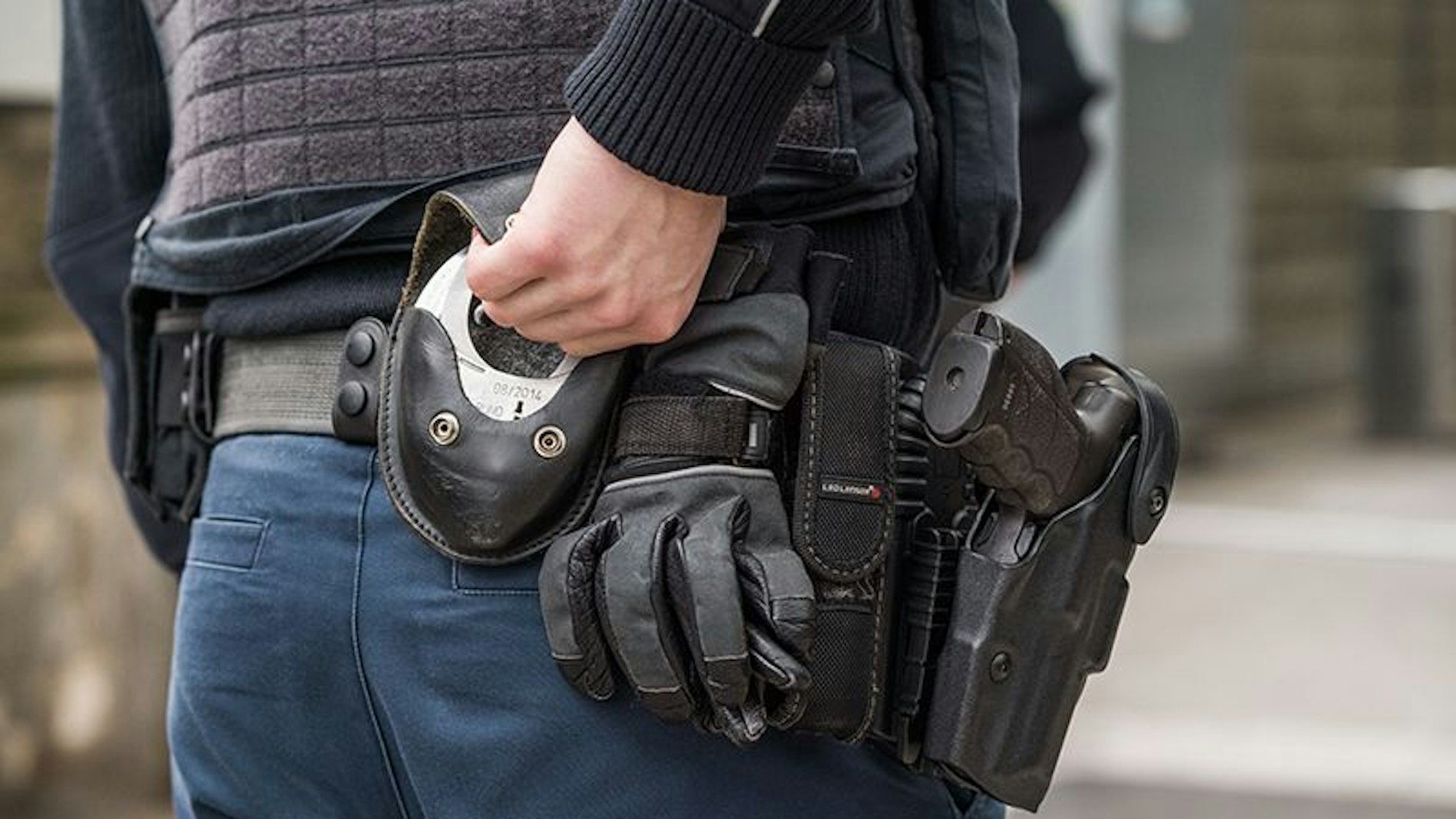 Der Rücken eines Bundespolizisten, der gerade nach hinten in seinen Gürtel greift, um Handschellen hervor zu holen.