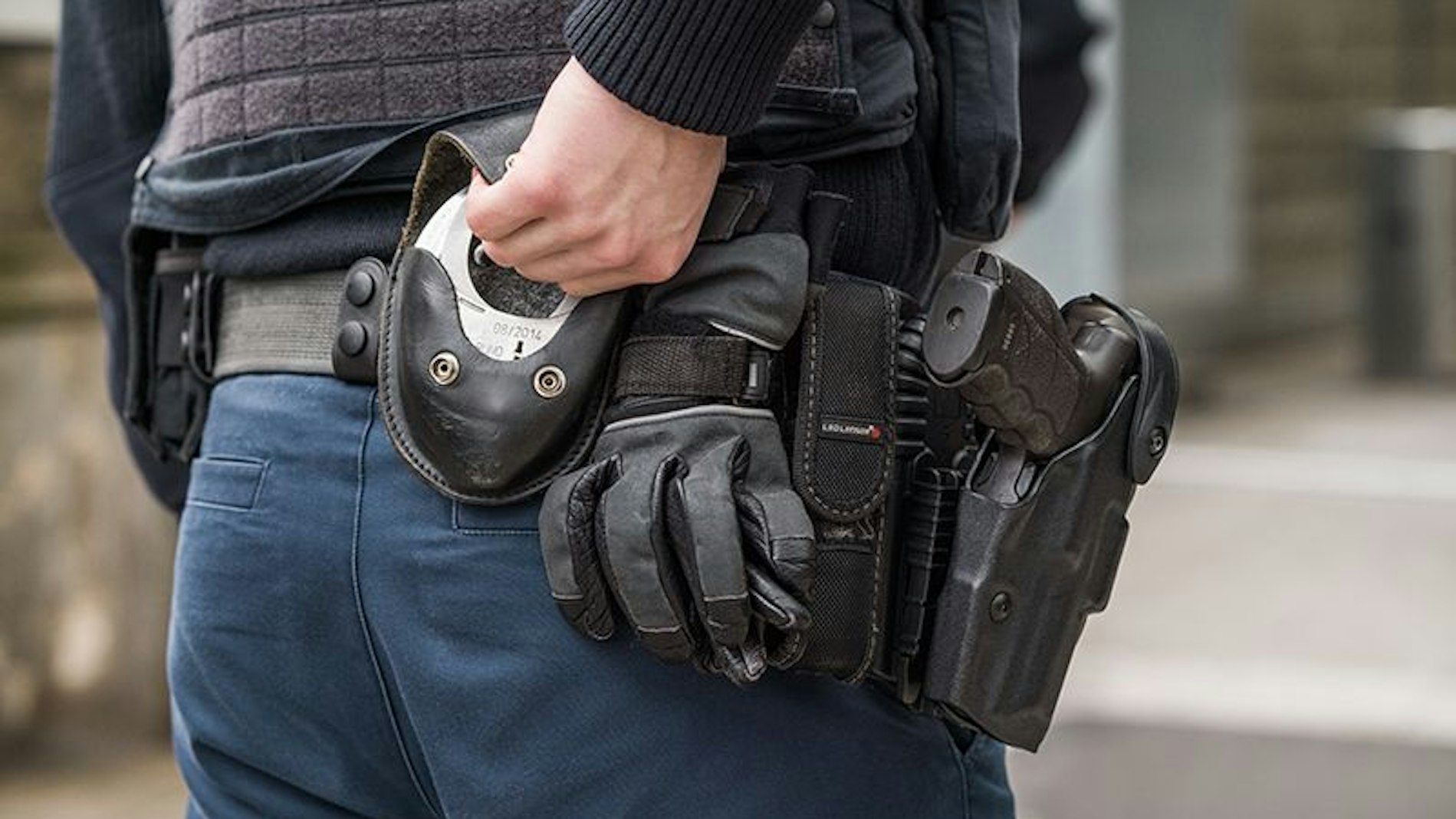Ein Beamter der Bundespolizei greift zu seinen Handschellen hinten an der Hosentasche.