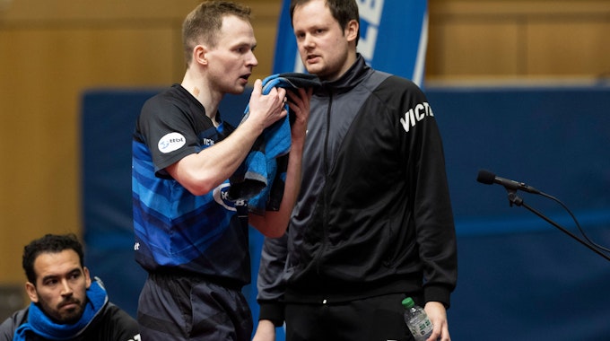 Schwalbe-Trainer Frederick Duda und sein Bruder und Spitzenspieler Benedikt Duda stehen in einer Sporthalle nebeneinander.