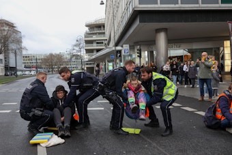 Polizisten tragen die Demonstranten von der Straße.