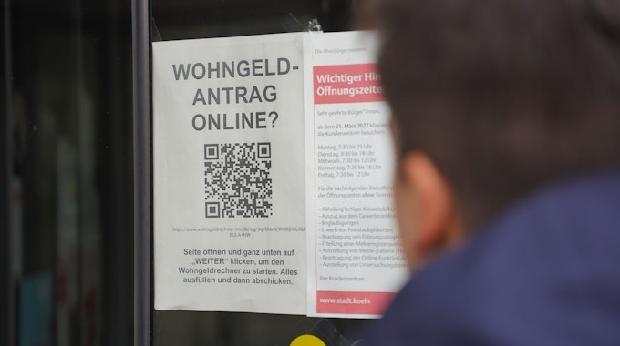 Im Fenster eine Kölner Behörde ist ein Hinweis auf die Online-Beantragung des Wohngeldes ausgehängt.