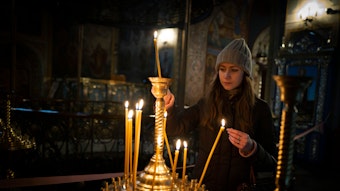 Ukraine, Kiew: Ein Mädchen zündet eine Kerze vor Beginn des orthodoxen Weihnachtsfestes im St. Michaels-Kloster an.