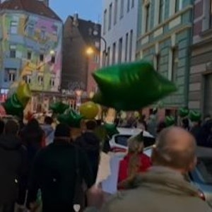 Fans ziehen mit grünen Luftballons durch Köln und feiern die Kölner Gaststätte Oma Kleinmann mit einer besonderen Aktion zum 20. Geburtstag.
