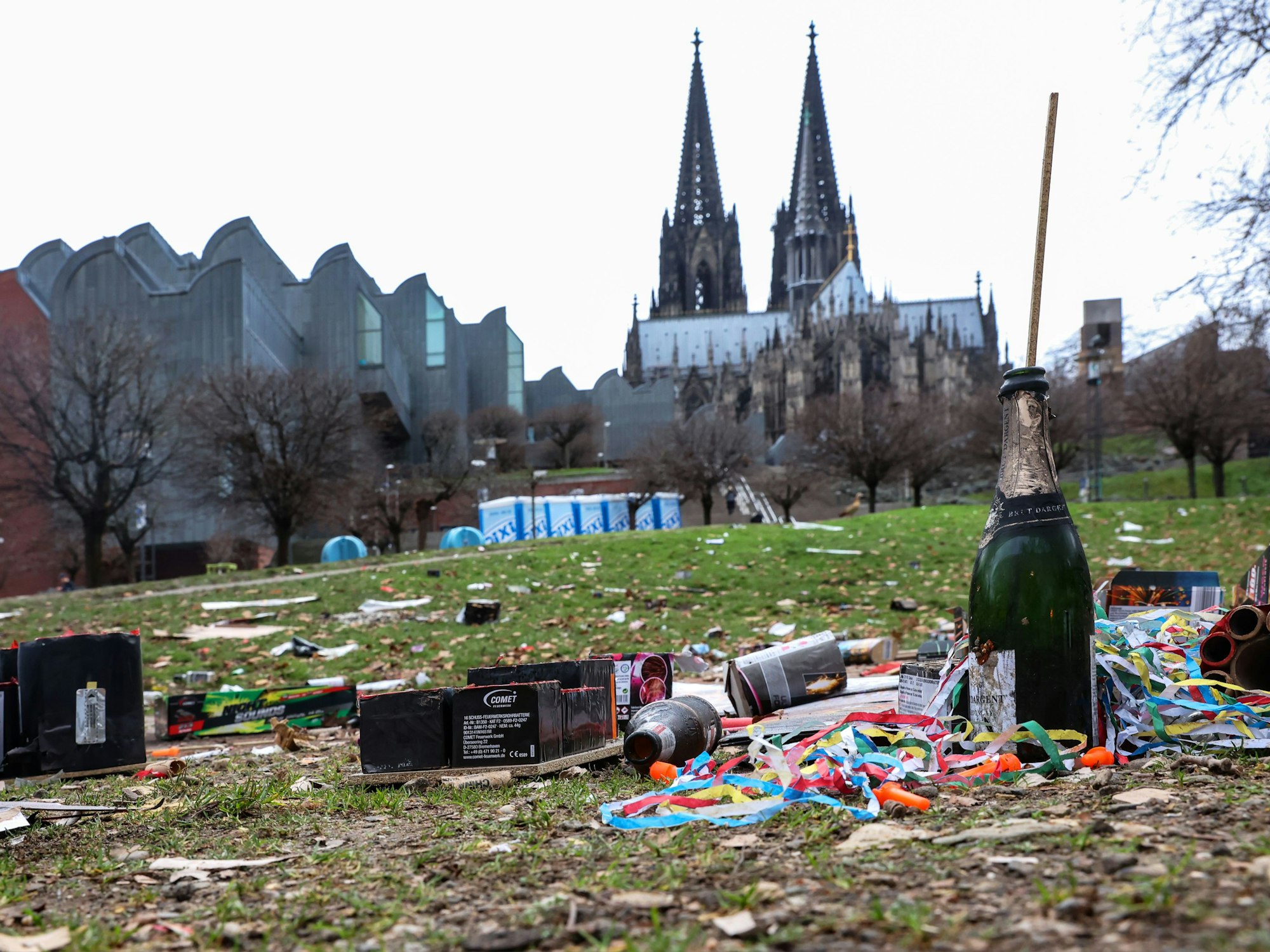 Müll liegt nach Silvester im Rheingarten in Köln. Im Hintergrund ragt der Kölner Dom hervor.