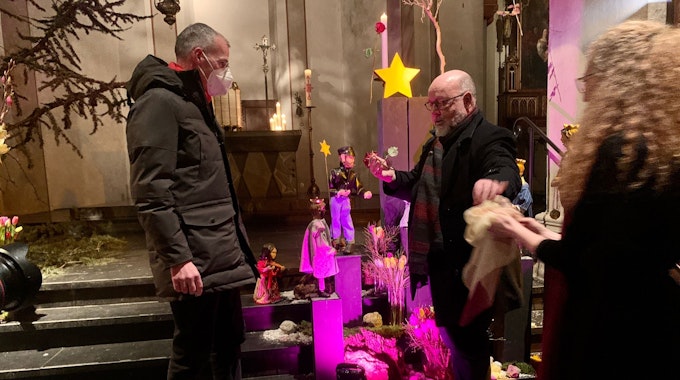 Pfarrer Bernd Mönkebüscher (l.) und der Kölner Pfarrer Benjamin Marx enthüllen eine neue Krippenfigur.