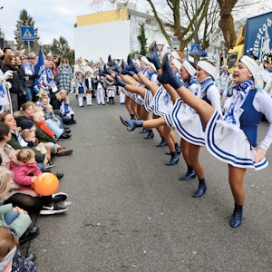 Die Mädchen- und Frauengarde der Opladener Altstatfunken tanzt auf der rechten Seite und hat die Beine in der Luft, links schauen Familien dem Treiben zu.