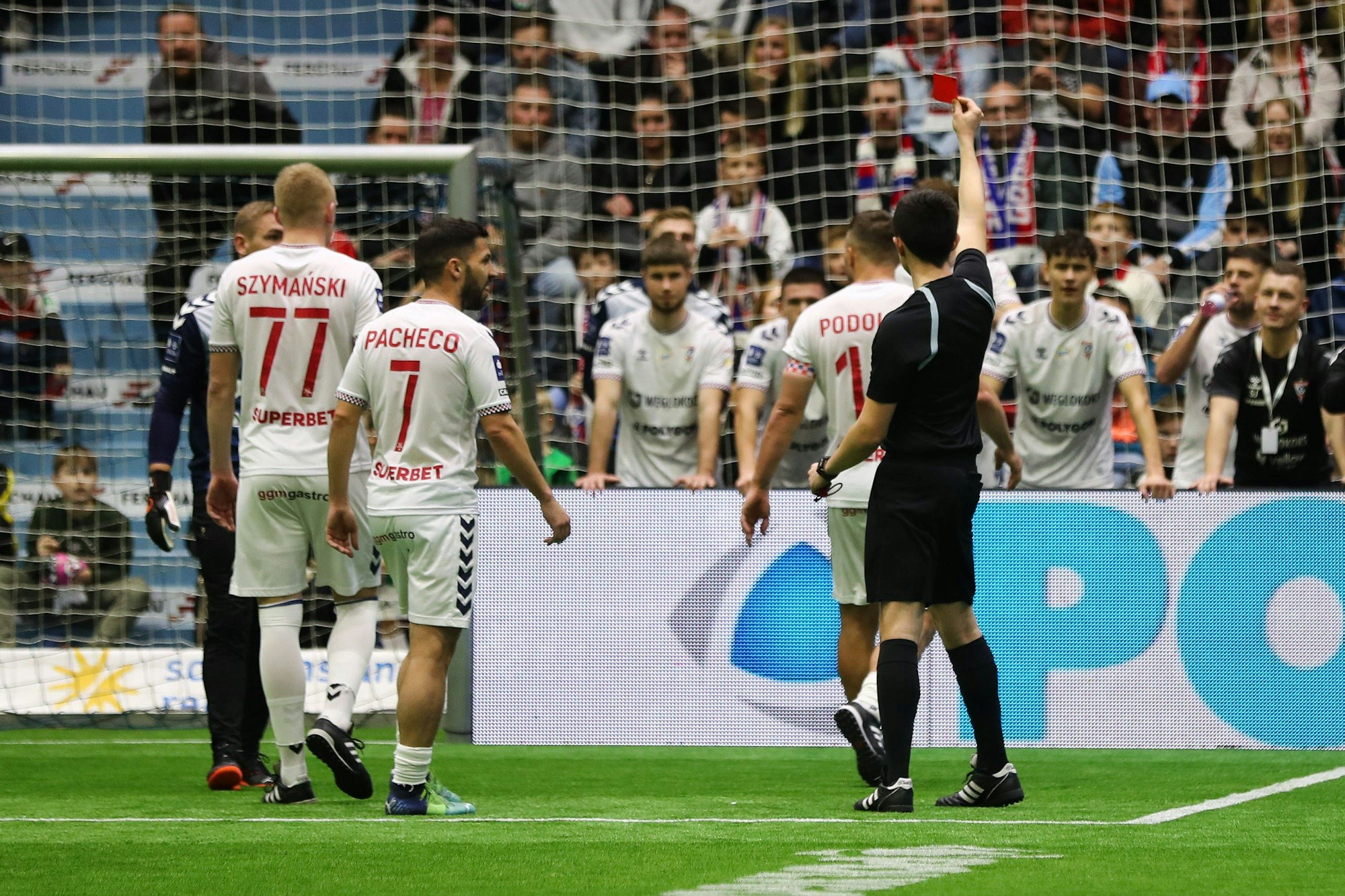 Lukas Podolski geht von einem Fußballfeld, ein Schiedsrichter zeigt ihm die Rote Karte.