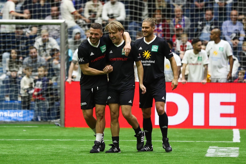 Lukas Podolski ubelt mit Markus Krampe Poldi und Rúrik Gislason über das 1:0 beim Promi-Kick für den guten Zweck.