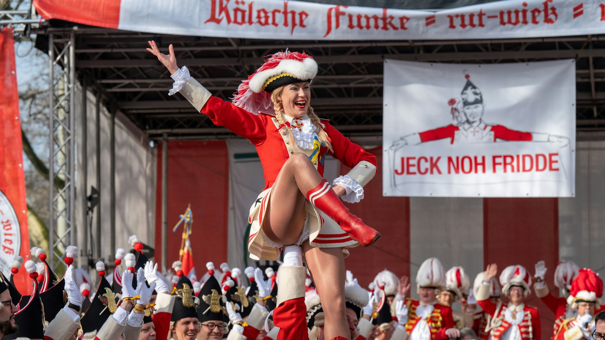Tanzmariechen beim Funkenbiwak der Roten Funken am Neumarkt. Im Hintergrund ein Transparent „Jeck noh Fridde“ gegen den Krieg Russlands in der Ukraine.