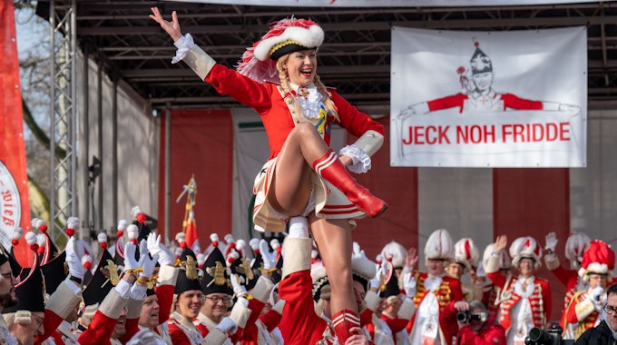 Tanzmariechen beim Funkenbiwak der Roten Funken am Neumarkt. Im Hintergrund ein Transparent „Jeck noh Fridde“ gegen den Krieg Russlands in der Ukraine.&nbsp;