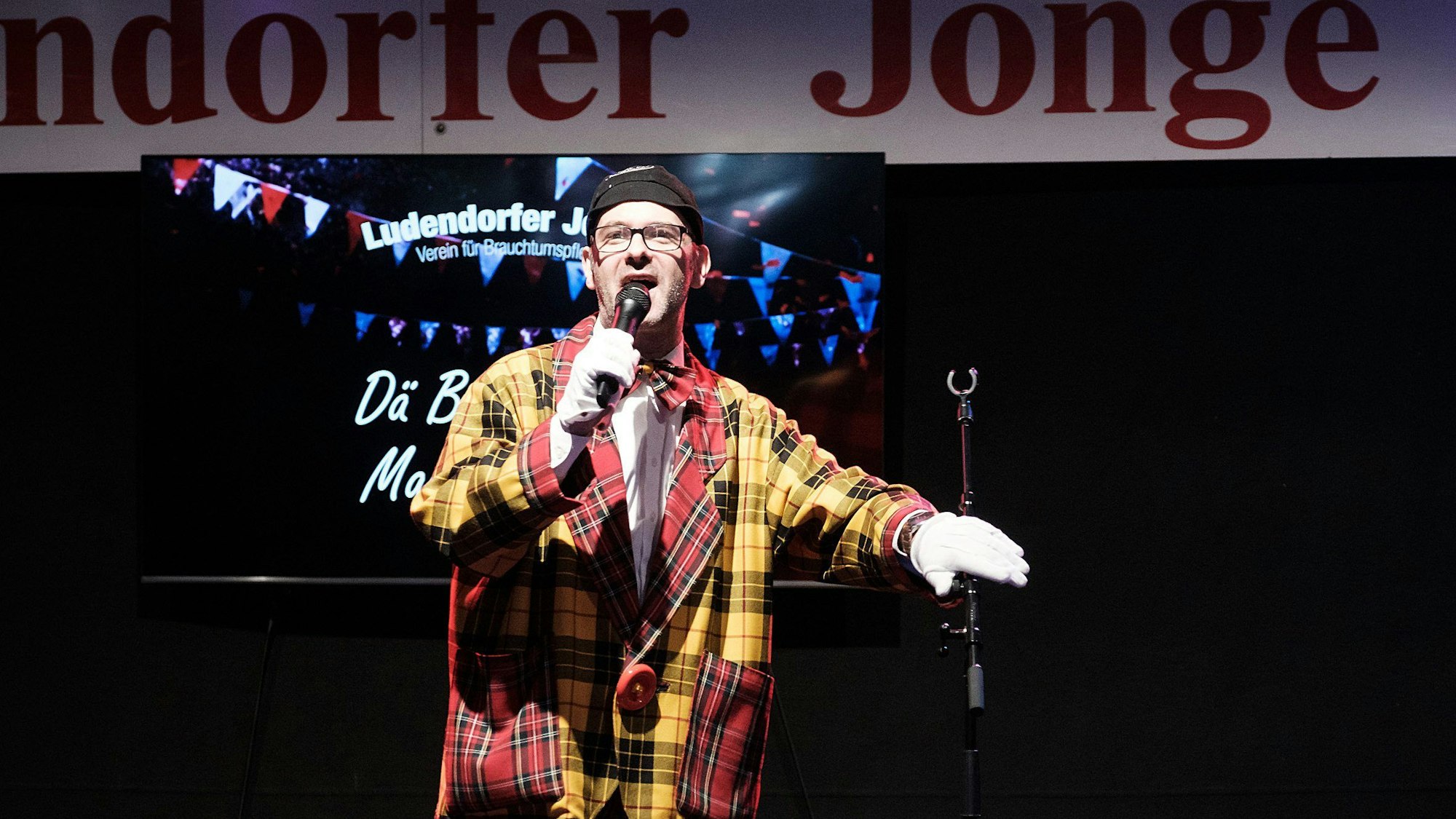Marc Metzger steht im Clownskostüm bei der Herrensitzung der Ludendorfer Jonge in Morenhoven auf der Bühne