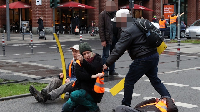 Klimakleber auf der Pipinstraße. Ein Mann versucht, Demonstrierende mit Gewalt von der Straße zu zerren.