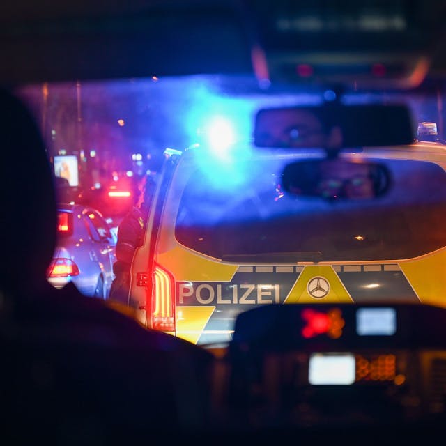 Blick durch die Frontscheibe auf das Heck eines weiteren Polizeiautos mit eingeschaltetem Blaulicht.