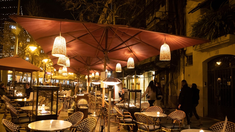 Das undatierte Symbolfoto zeigt den Außenbereich eines Restaurants mit Tischen, Stühlen und Laternen, die an Sonnenschirmen befestigt sind.