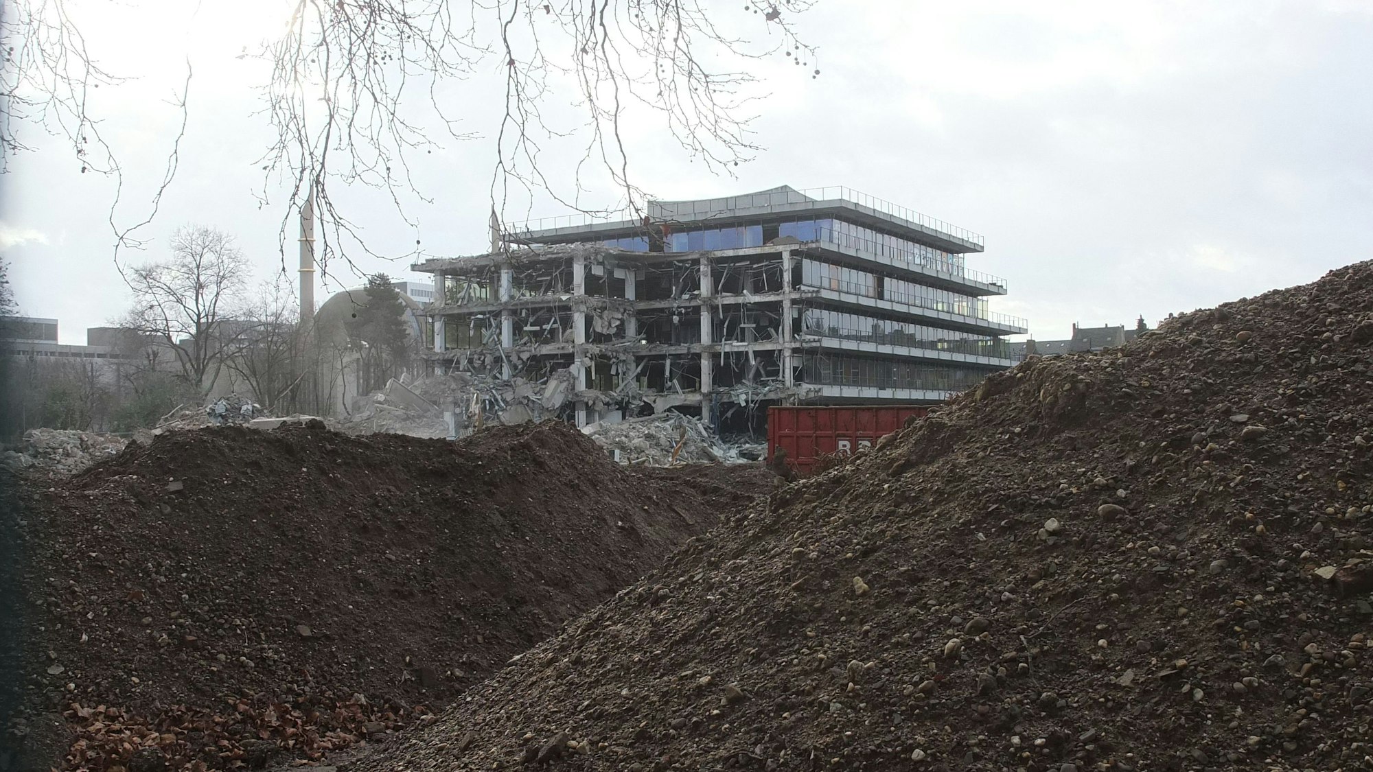 Die Abbrucharbeiten am Siemensgebäude liefern Bilder einer bizarren Endzeit-Szenerie. Hinter Erdhägeln steht das halb abgerissene Gebäude.