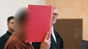 Der Angeklagte steht in einem Saal vom Landgericht. Der Kopf des Mannes ist auf dem Bild unkenntlich gemacht.