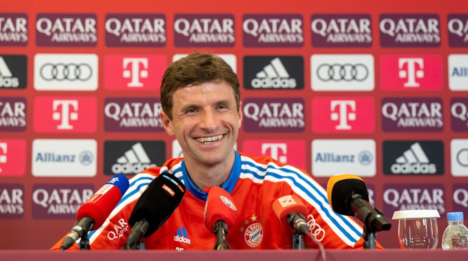 Thomas Müller lacht auf einer Pressekonferenz des FC Bayern München.