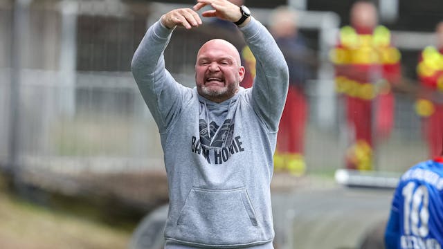 Trainer Alexander Voigt gestikuliert mit beiden Händen über dem Kopf und kündigt einen Wechsel an.