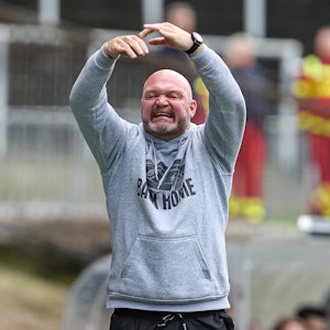 Trainer Alexander Voigt gestikuliert mit beiden Händen über dem Kopf und kündigt einen Wechsel an.