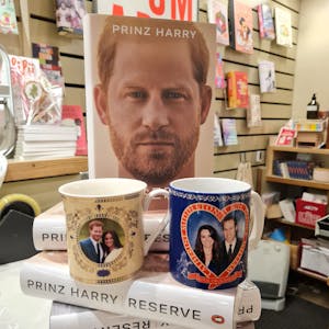 Auf einem kleinen Stapel des Buches von Prinz Harry steht eine Tasse mit dem Foto von Harry und Meghan und eine mit dem Foto von William und Kate.&nbsp;
