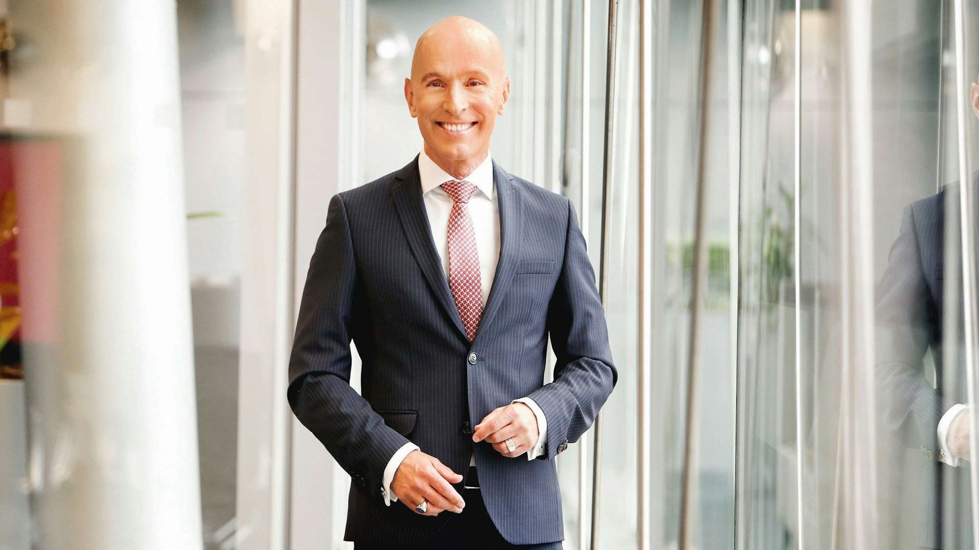Ein Porträtfoto des RTL-Adelsexperten Michael Begasse. Er lächelt in die Kamera und trägt einen schwaren Anzug mit Nadelstreifen.