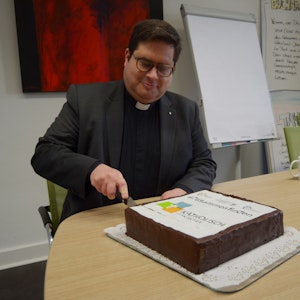 1Pfarrer Tobias Hopmann schneidet den Kuchen an, der das Logo der neuen pastoralen Einheit Euskirchen zeigt.