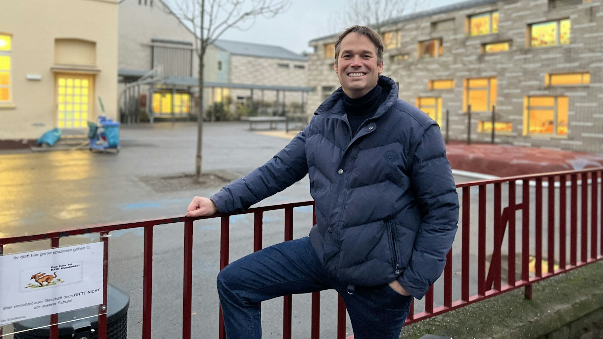 Thomas Heidbrink, der Schulpflegschaftsvorsitzender der GGS Hohe Straße steht am Zaun vor der Schule und lächelt.