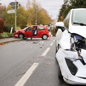 Ein beschädigter weißer Wagen steht nach einem Verkehrsunfall in Oberbantenberg mitten auf der Straße, der rote Unfall-Pkw im Hintergrund ist auf dem Fußgängerweg gefahren.