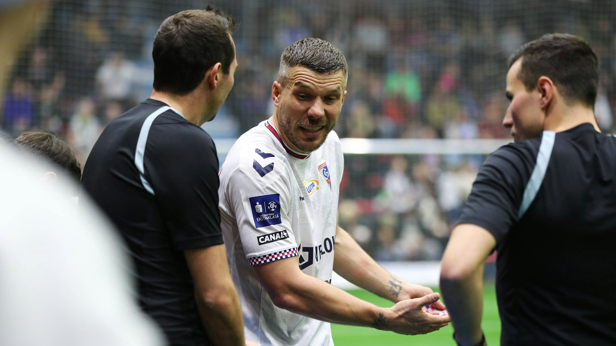 Lukas Podolski diskutiert mit den Schiedsrichtern.