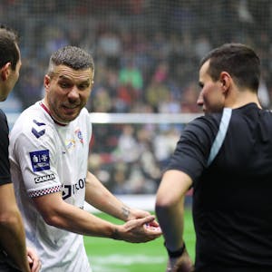 Lukas Podolski diskutiert mit den Schiedsrichtern.