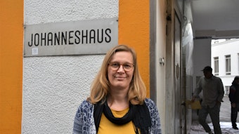 Die Leiterin des Johanneshauses vor einem Schild mit der Aufschrift: Johanneshaus.