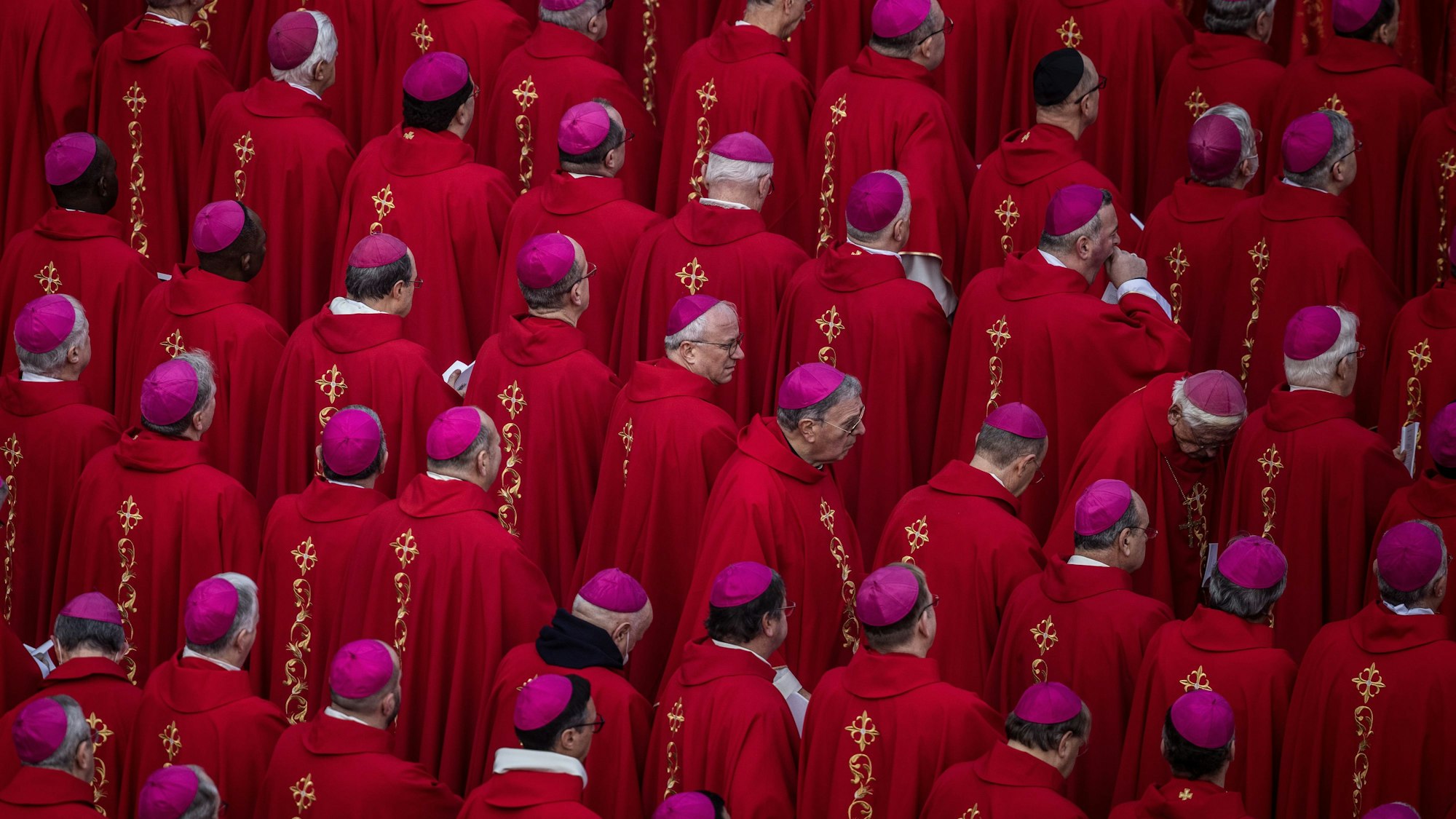 Katholische Bischöfe nehmen an der öffentlichen Trauermesse für den emeritierten Papst Benedikt XVI. auf dem Petersplatz teil. Sie tragen rote Messgewänder und Scheitelkäppchen in der Bischofsfarbe violett.