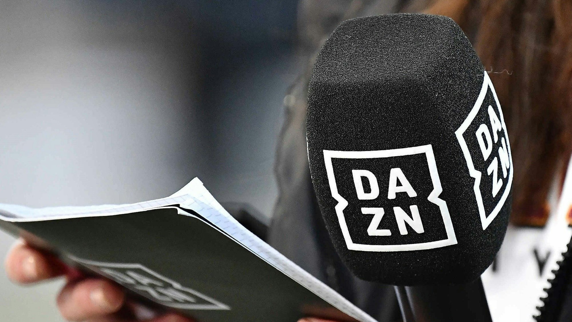 Ein Mikrofon und Moderations-Kärtchen mit dem Logo von DAZN bei einer Bundesliga-Übertragung.