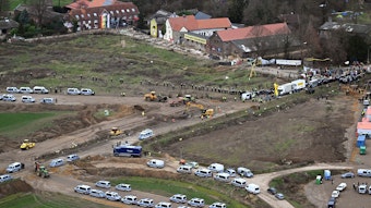 Polizeiautos und Polizisten stehen vor der Ortschaft Lützerath - eine Luftaufnahme zeigt die Szenerie. Lützerath soll zur Erweiterung des Braunkohletagebaus Garzweiler II abgebaggert werden.