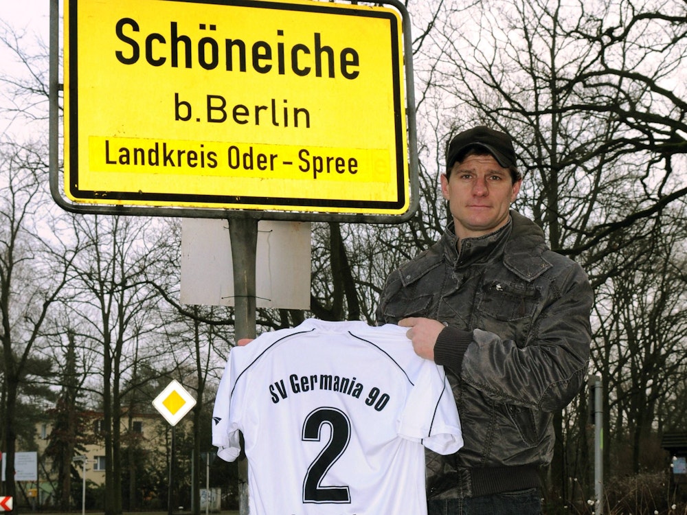 Steffen Baumgart (Germania Schöneiche) präsentiert sein Trikot am Ortsschild von Schöneiche.