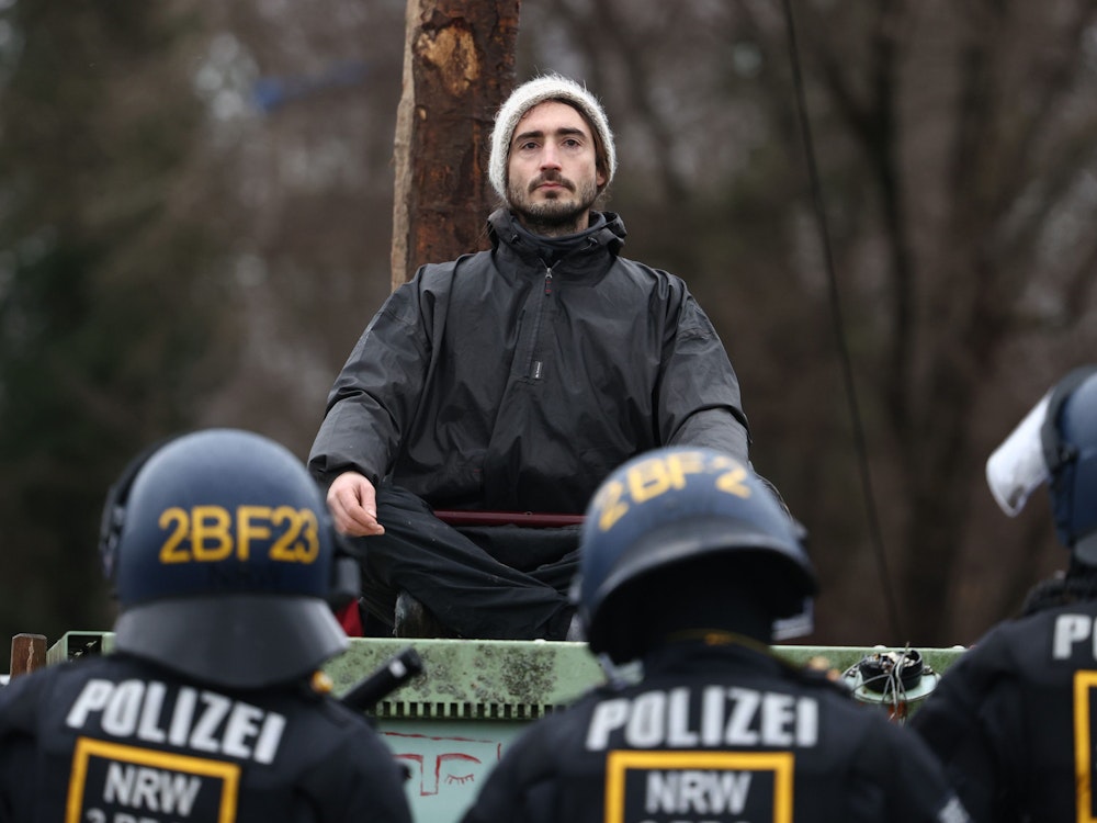 Polizisten rücken in den von Klimaaktivisten besetzten Braunkohleort Lützerath vor und stehen einem Aktivisten gegenüber.