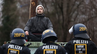Polizisten rücken in den von Klimaaktivisten besetzten Braunkohleort Lützerath vor und stehen einem Aktivisten gegenüber.