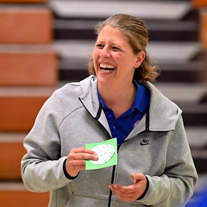 Eine Basketballtrainerin steht lachend am Spielfeldrand.