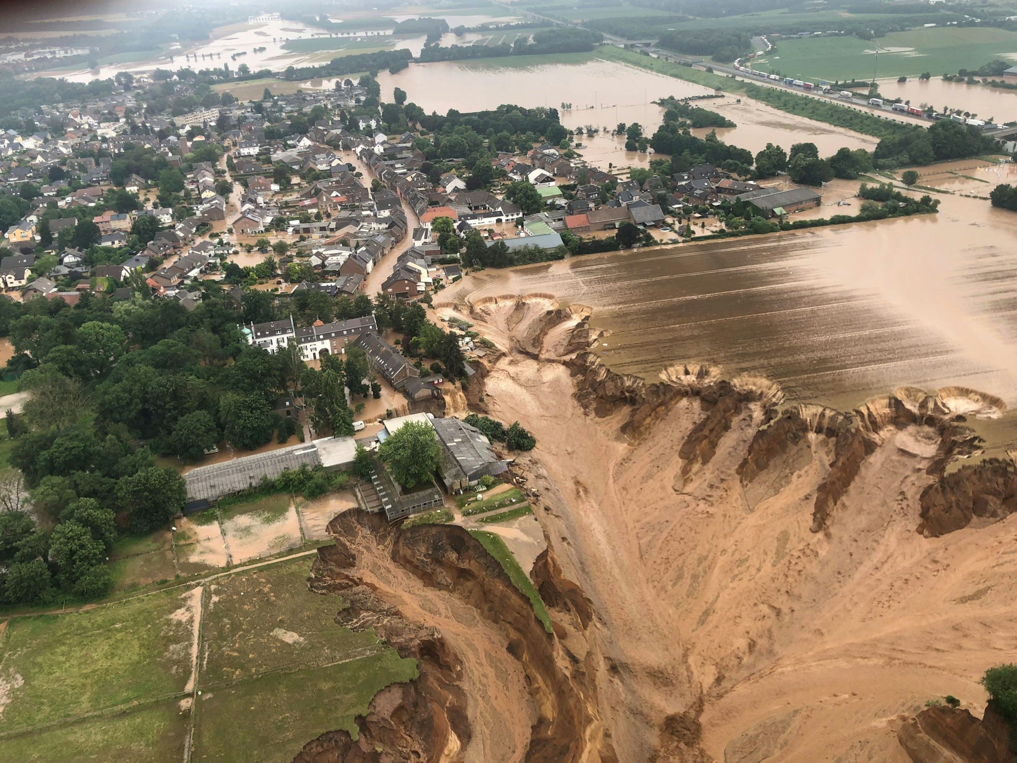 Ein Foto, das die Bezirksregierung Köln über Twitter verbreitete, zeigt Überschwemmungen in Erftstadt-Blessem. Ein Krater an der Kiesgrube hat mehrere Häuser mit sich gerissen.
