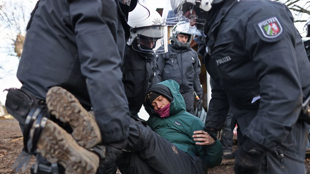 Polizisten tragen bei der Räumung von Lützerath eine Demonstrantin fort.