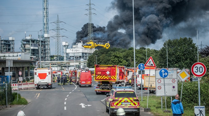 Feuerwehr, Rettungsfahrzeuge und ein Hubschrauber sind nach der Explosion in Bürrig vor der stark qualmenden Sondermüllverbrennung zu sehen