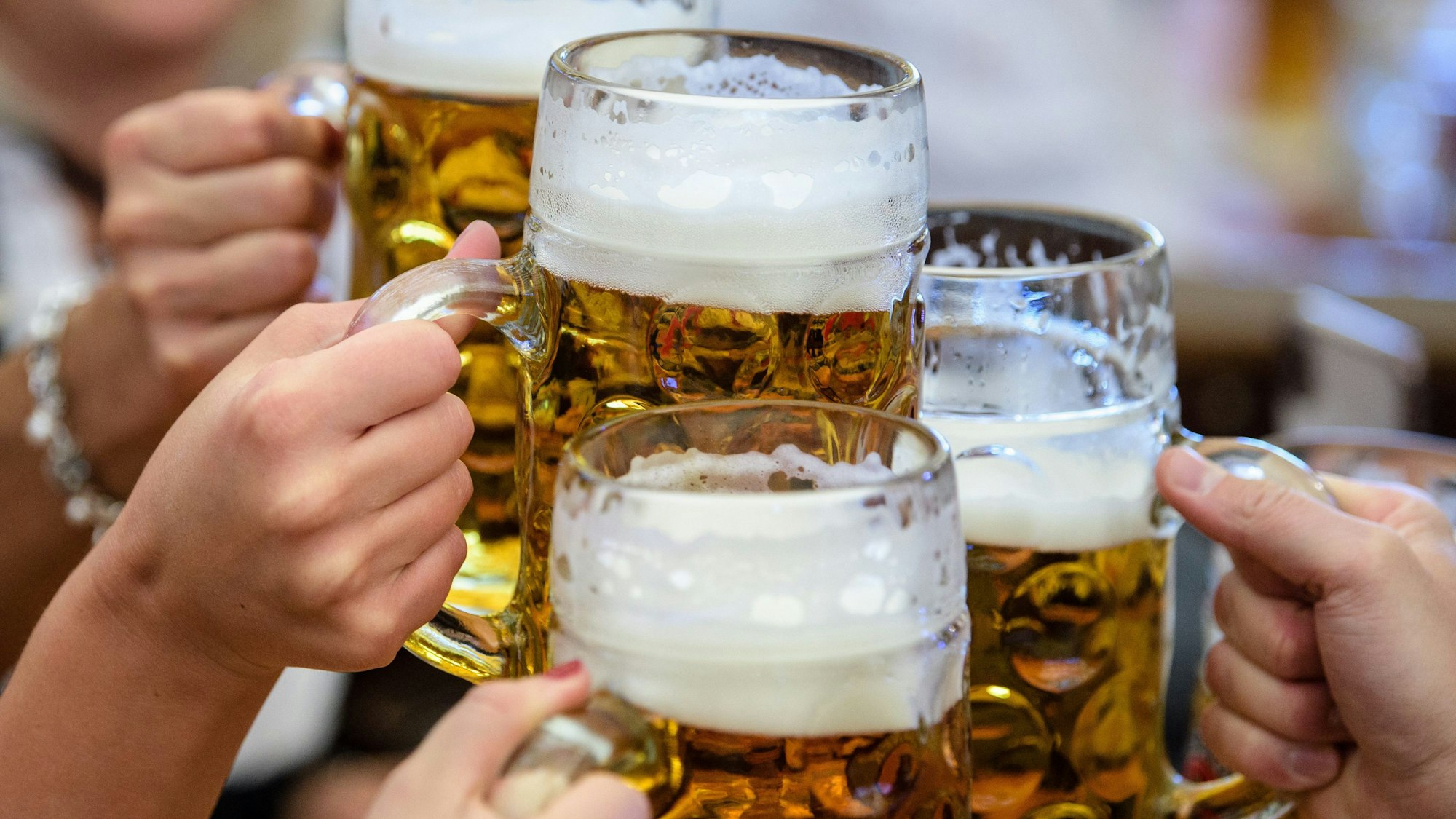 Besucherinnen und Besucher prosten sich beim Auftakt zum Oktoberfest in München im Paulaner-Festzelt mit ihrer ersten Maß Bier zu.