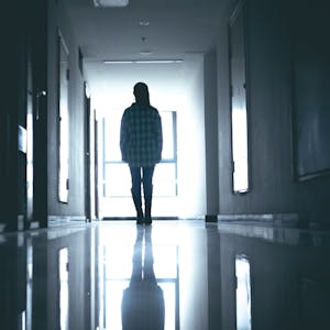 Eine junge Frau steht verlassen in einem dunklen Krankenhausflur.&nbsp;