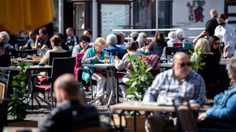 In die Euskirchener Innenstadt, hier einige Personen an Tischen der Außengastronomie im März 2022, kehrt das Leben zurück. Doch es ist noch viel Aufbauarbeit nötig.