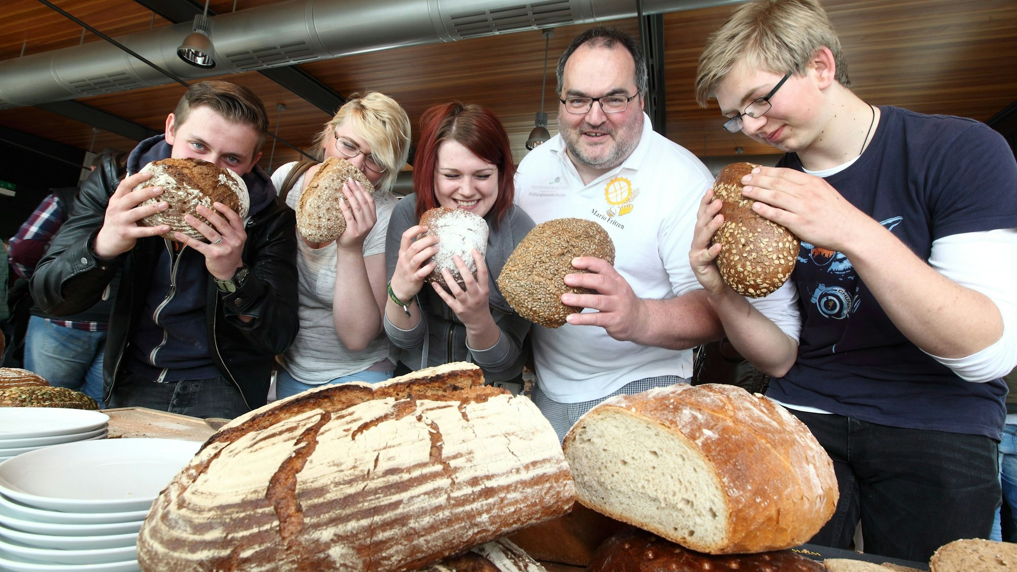 Der Kürtener Bäckermeister Mario Fritzen und sein Team halten Brotlaibe in der Hand.