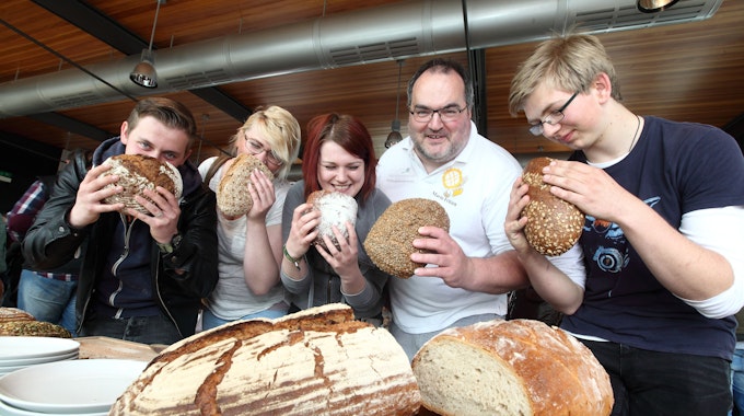 Der Kürtener Bäckermeister Mario Fritzen und sein Team halten Brotlaibe in der Hand.